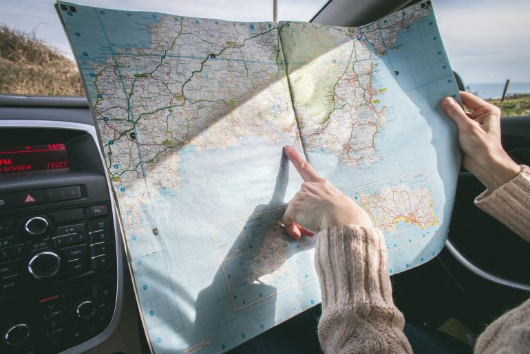 person wearing beige sweater holding map inside vehicle