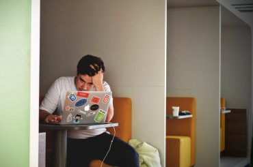 man in white shirt using macbook pro