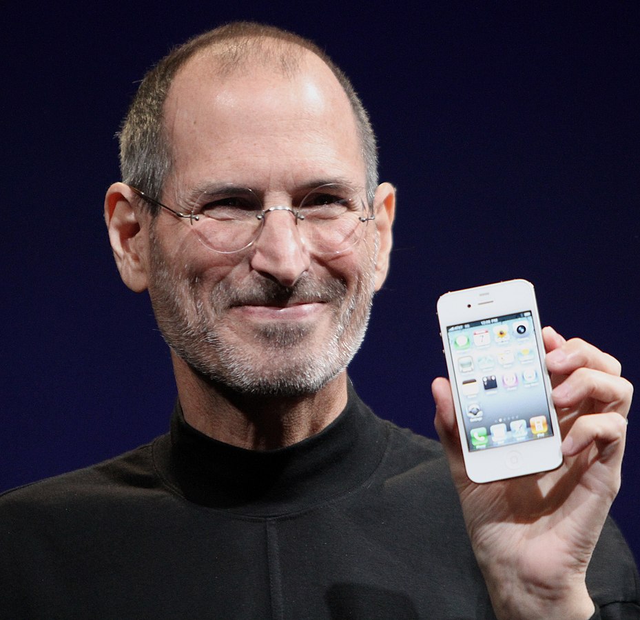 Contoh alt text tanpa keyword stuffing: Founder Apple, Steve Jobs, sedang memegang iPhone 4